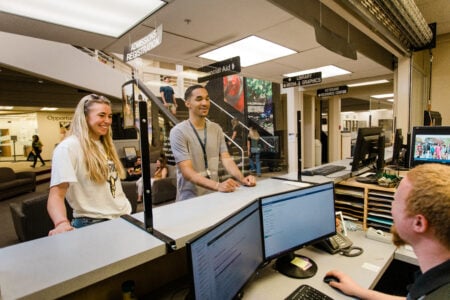 Two students standing at Admissions desk receiving assistance