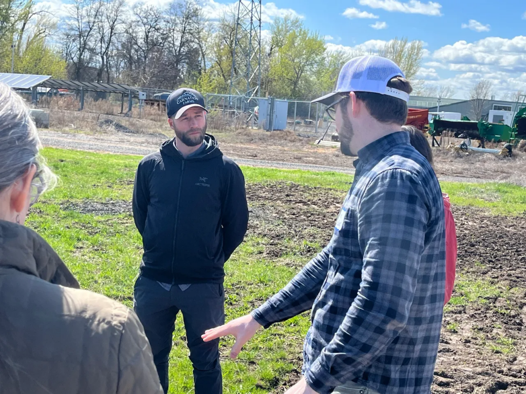 Alan Raeder, with his hand out, talks about their in-field education with the group, including Eric Popp of Carnation Farms (black jacket).