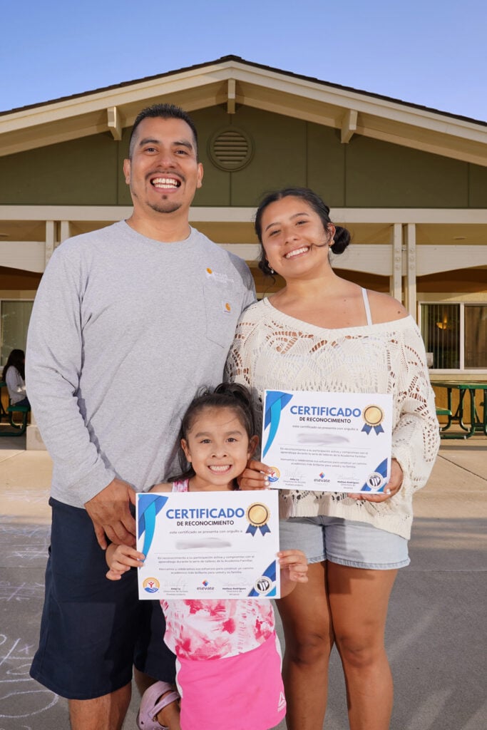 Hispanic family proudly holding up a learning certificate