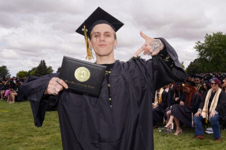Proud male student pointing to his graduation certificate.