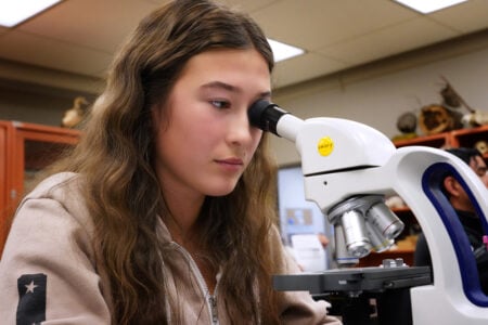 Female student looking into a microscope.