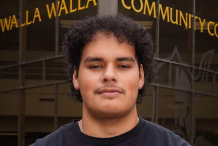 Smiling student in front of a college building.