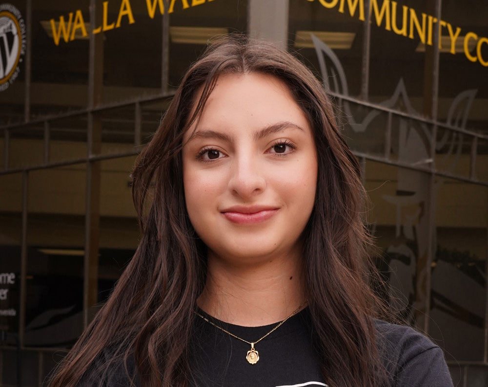 Smiling student in front of a college building.