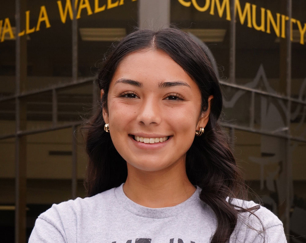 Smiling student in front of a college building.