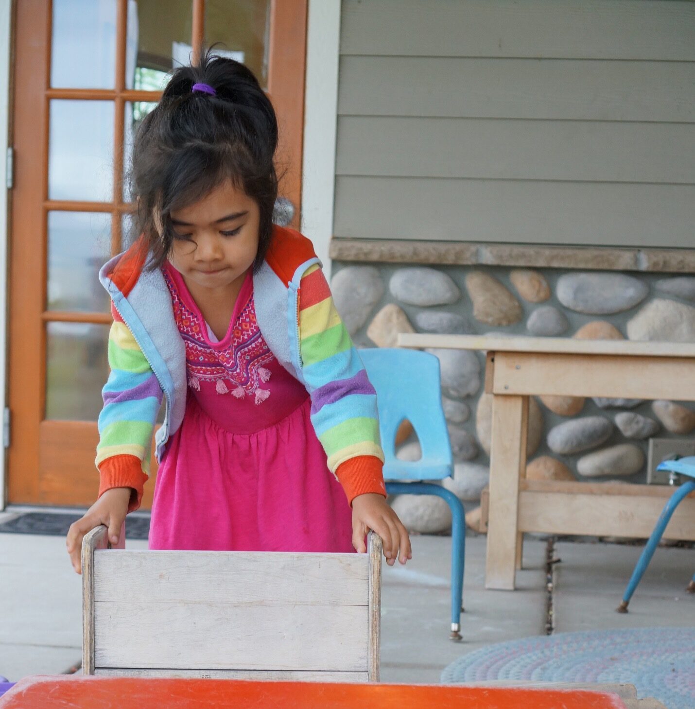 child playing with wooden blocks front of parent center entrance