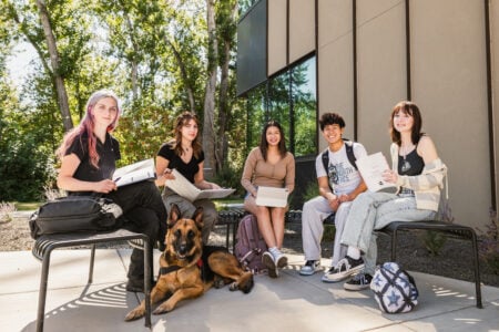 Group of Running Start students sitting on benches outside of the Main Building D Science Wing