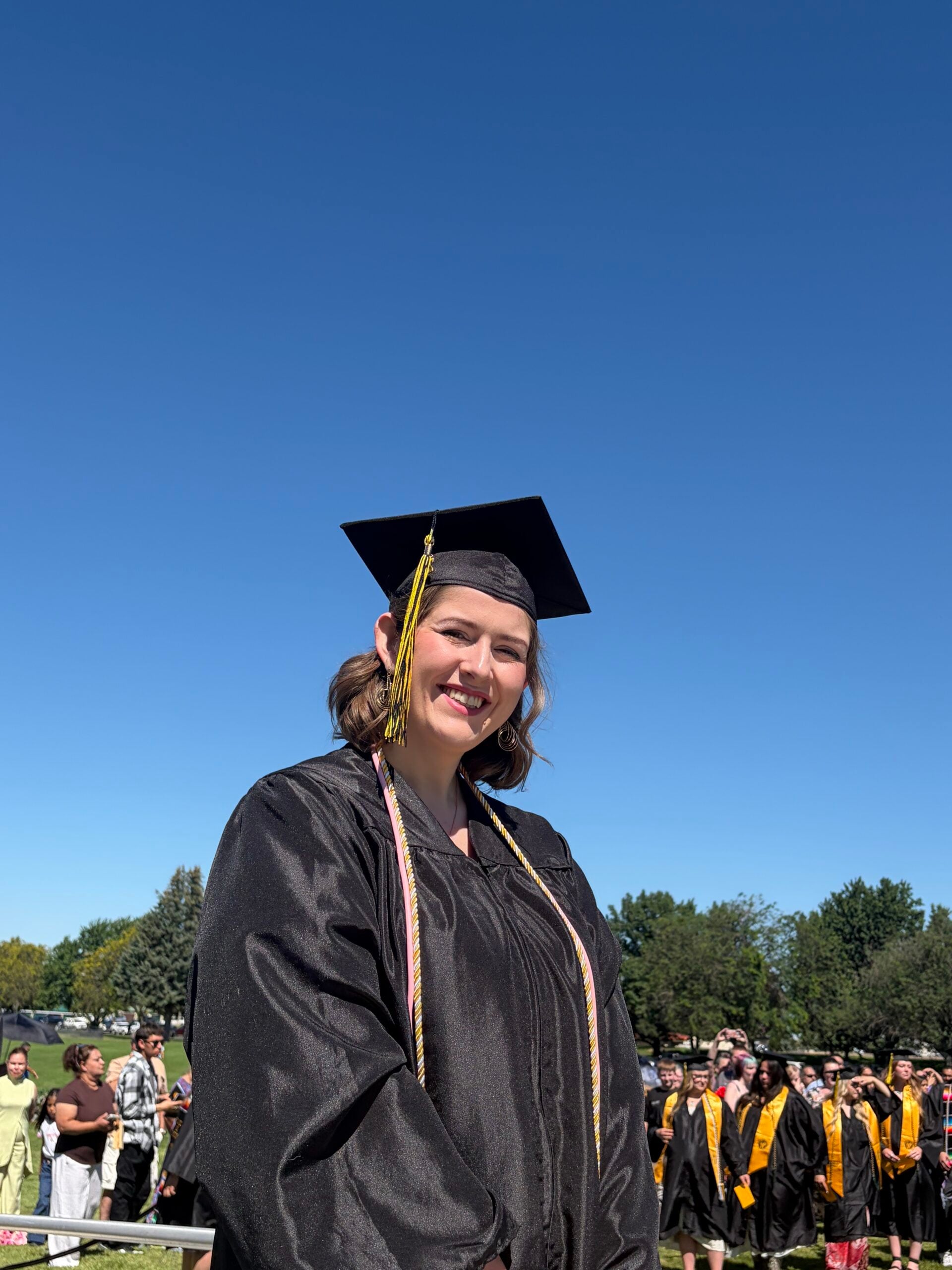 Graduate in cap and gown making a peace sign during a WWCC commencement ceremony.