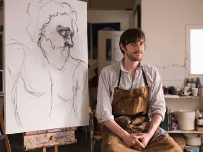 Portrait of man sitting by sketch in art class