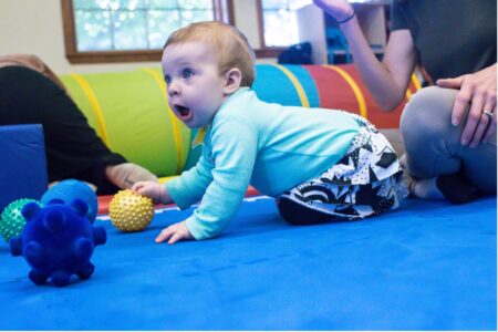 baby playing with plastic balls on carpet