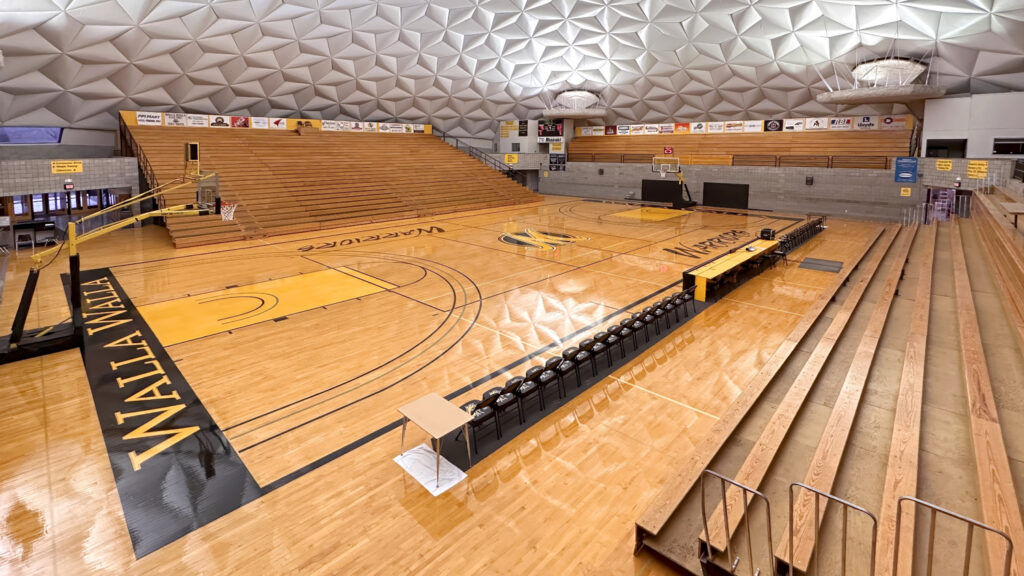Interior of a large gymnasium with a distinctive geodesic dome ceiling. A full basketball court with 