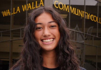 Smiling student in front of a college building.